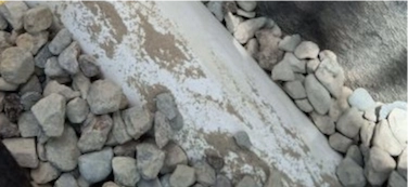 French Drain and Water Barrier Project in Discovery Bay 3 French Drain close up of drain rock, filter paper and perforated pipe